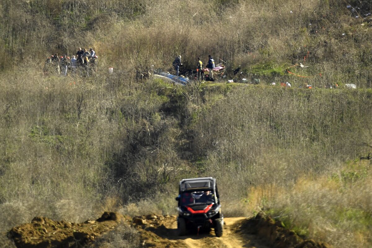 FILE - In this Monday, Jan. 27, 2020 file photo, investigators, top, work the scene of a helicopter crash that killed former NBA basketball player Kobe Bryant, his 13-year-old daughter, Gianna, and seven others as Los Angeles County Sheriff's deputies patrol in an all-terrain vehicle on a hillside in Calabasas, Calif. Authorities are investigating whether deputies shared graphic photos of the crash scene, according to a Los Angeles Times report quoting an unnamed source. Los Angeles County Sheriff's Deputy Maria Lucero told The Associated Press on Friday, Feb. 28 that "the matter is being looked into." (AP Photo/Mark J. Terrill, File)