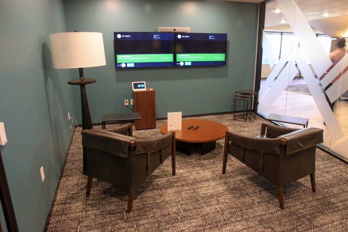 Two chairs are arranged facing screens mounted on a wall.