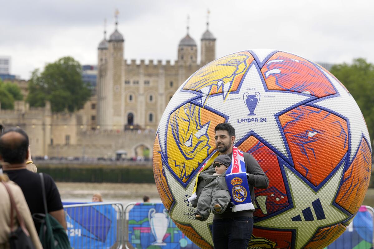 Football fans pose by a giant Champions L 