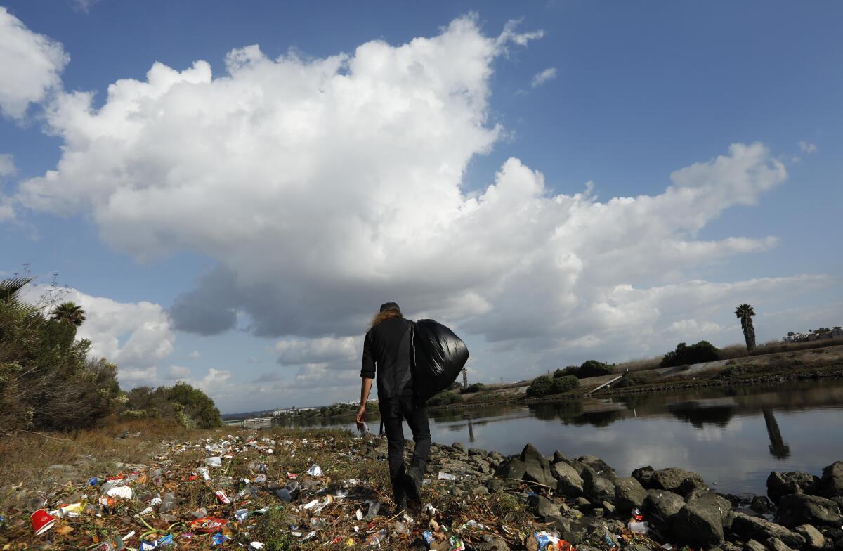 Josey Peters carries a bag of trash at Ballona Creek