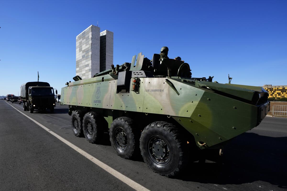An armored vehicle drives past Congressional buildings as part of a convoy after it passed by Planalto presidential palace in Brasilia, Brazil, Tuesday, Aug. 10, 2021. The convoy paraded by the palace on Tuesday, the day of a key congressional vote on a constitutional reform proposal supported by Bolsonaro that would add printed receipts to some of the nation’s electronic ballot boxes. (AP Photo/Eraldo Peres)