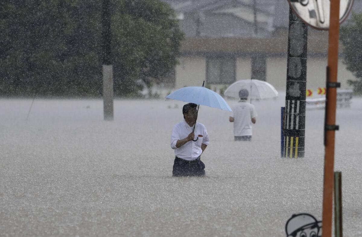 Personas caminan en una calle inundada por las fuertes lluvias,