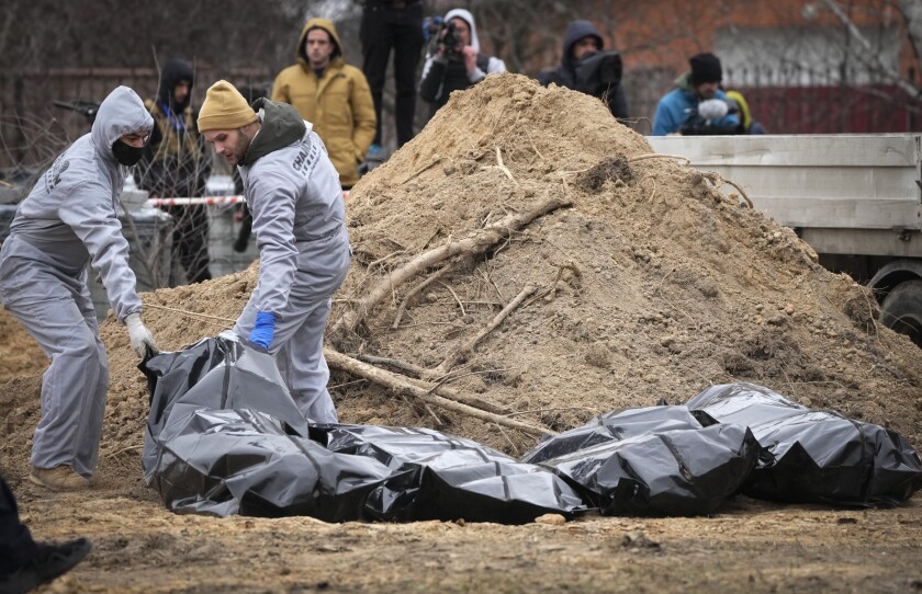Men wearing protective gear exhume the bodies of civilians killed during the Russian occupation in Bucha, in the outskirts of Kyiv, Ukraine, Wednesday, April 13, 2022. Dozens of bodies of civilians executed by the Russian troops have been exhumed already from the mass grave. (AP Photo/Efrem Lukatsky)
