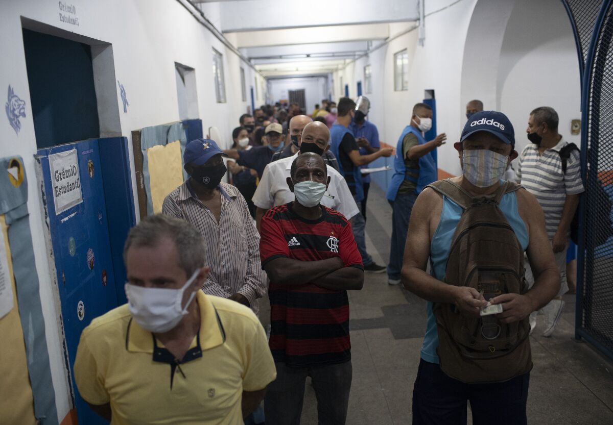 People wait in line to vote in municipal elections at a polling station at the Rocinha slum of Rio de Janeiro, Brazil, Sunday, Nov.15, 2020. Voters across Latin America's biggest country are electing mayors and municipal council members. (AP Photo/Silvia Izquierdo)