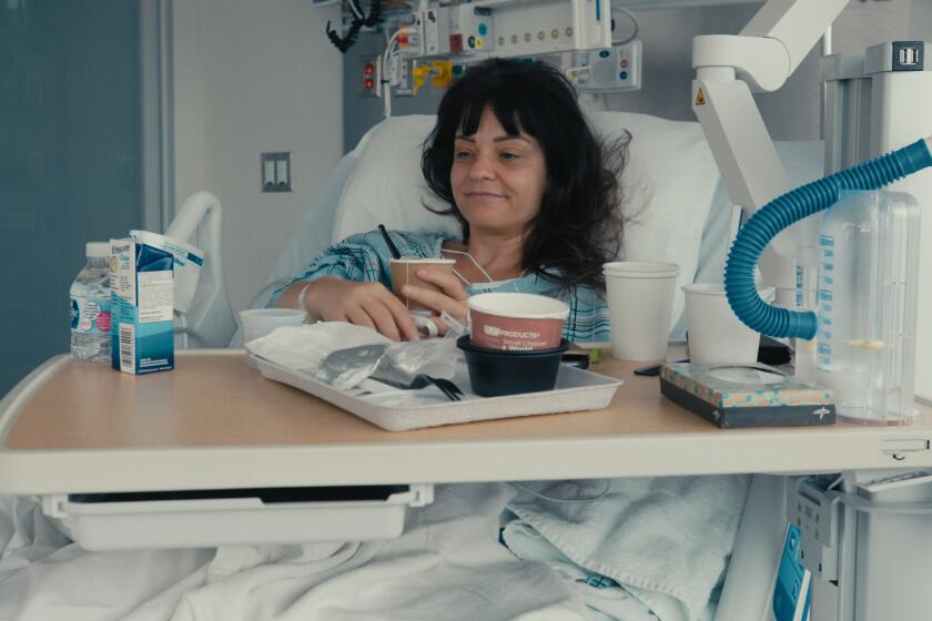 A woman smiles in a hospital bed.