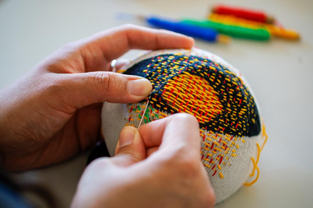 A close up of hands darning a sock.