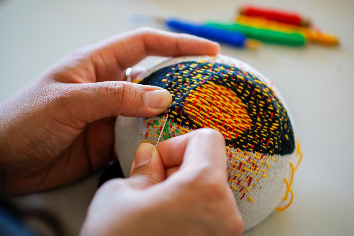 A close-up of hands mending a sock.