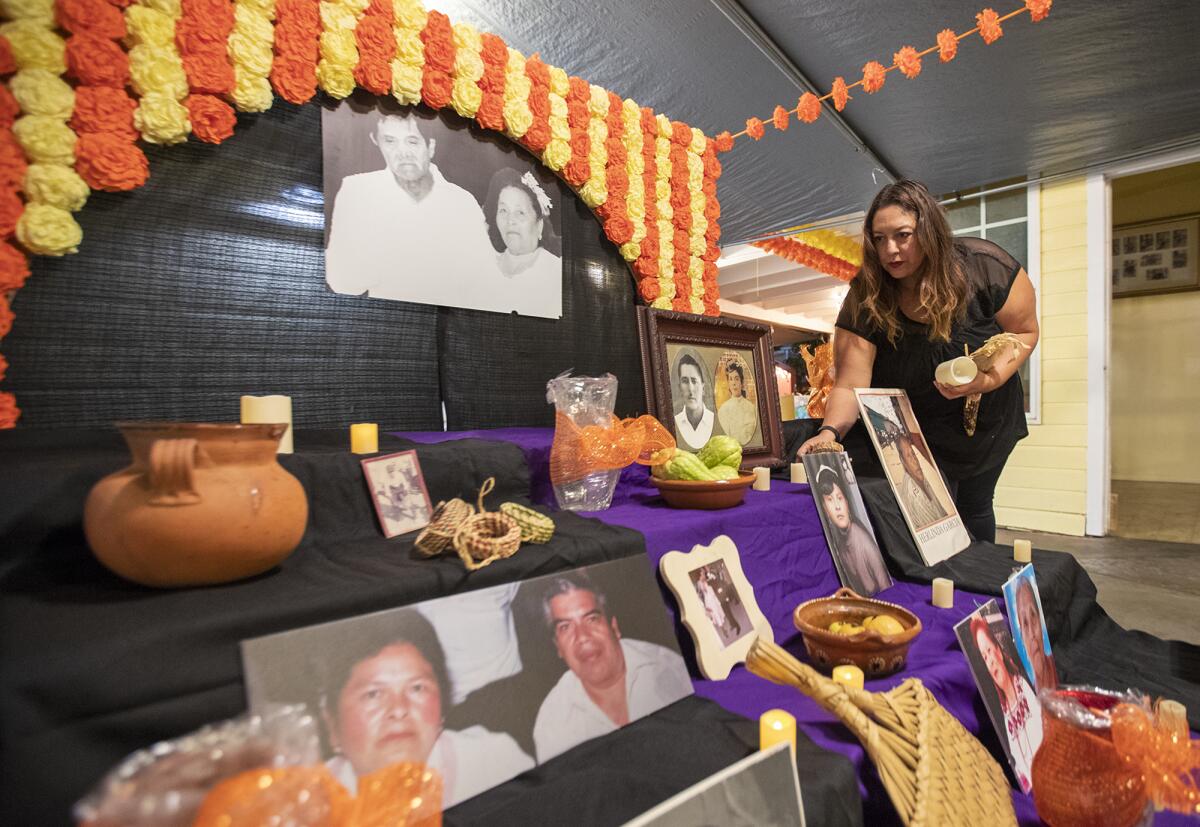 Nereida Prado oragnizes decorations on a family altar in preparation for the Day of the Dead celebration in Santa Ana.