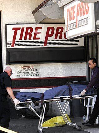 The body of a victim of an early morning shooting at Tire Pros in Simi Valley is removed by coroner officials. Another body found inside the store is believed to be that of the gunman, police say.