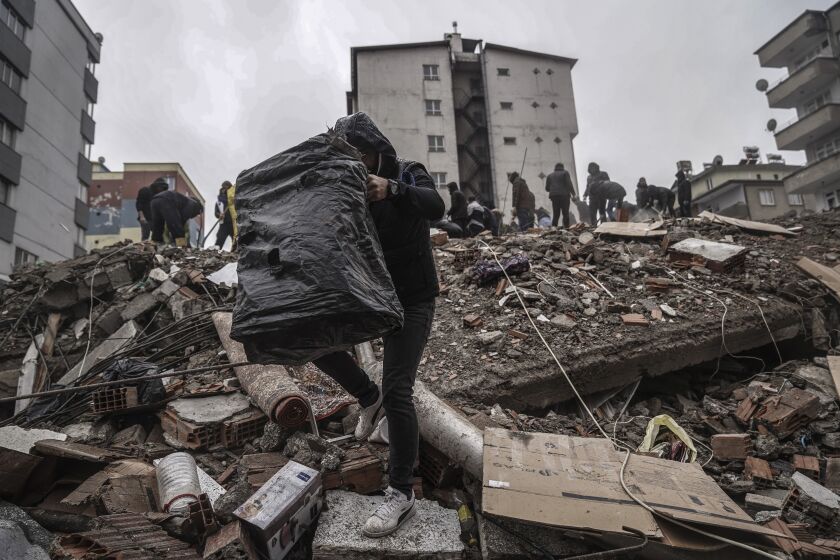 Varias personas y efectivos de los equipos de rescate buscan sobrevivientes entre los escombros de un edificio derrumbado por un temblor en Gaziantep, Turquía, el 6 de febrero de 2023. (AP Foto/Mustafa Karali)