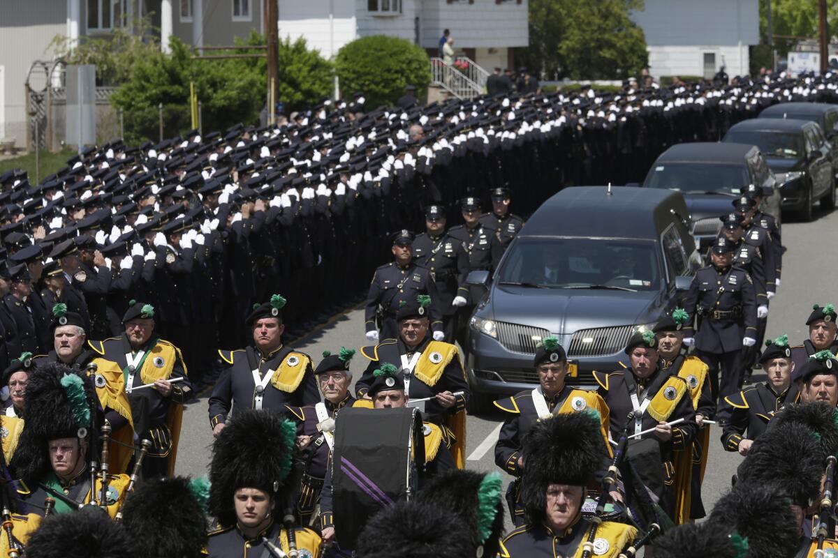 Police officers salute as the procession for Officer Brian Moore passes after his funeral Mass at the St. James Roman Catholic Church in Seaford, N.Y. The 25-year-old died two days after he was shot in Queens this month.