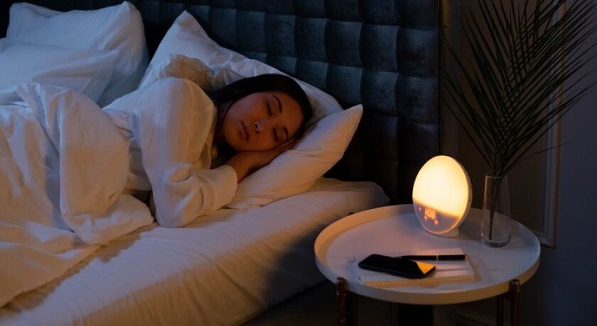 Sleeping person waking up with a light therapy alarm clock