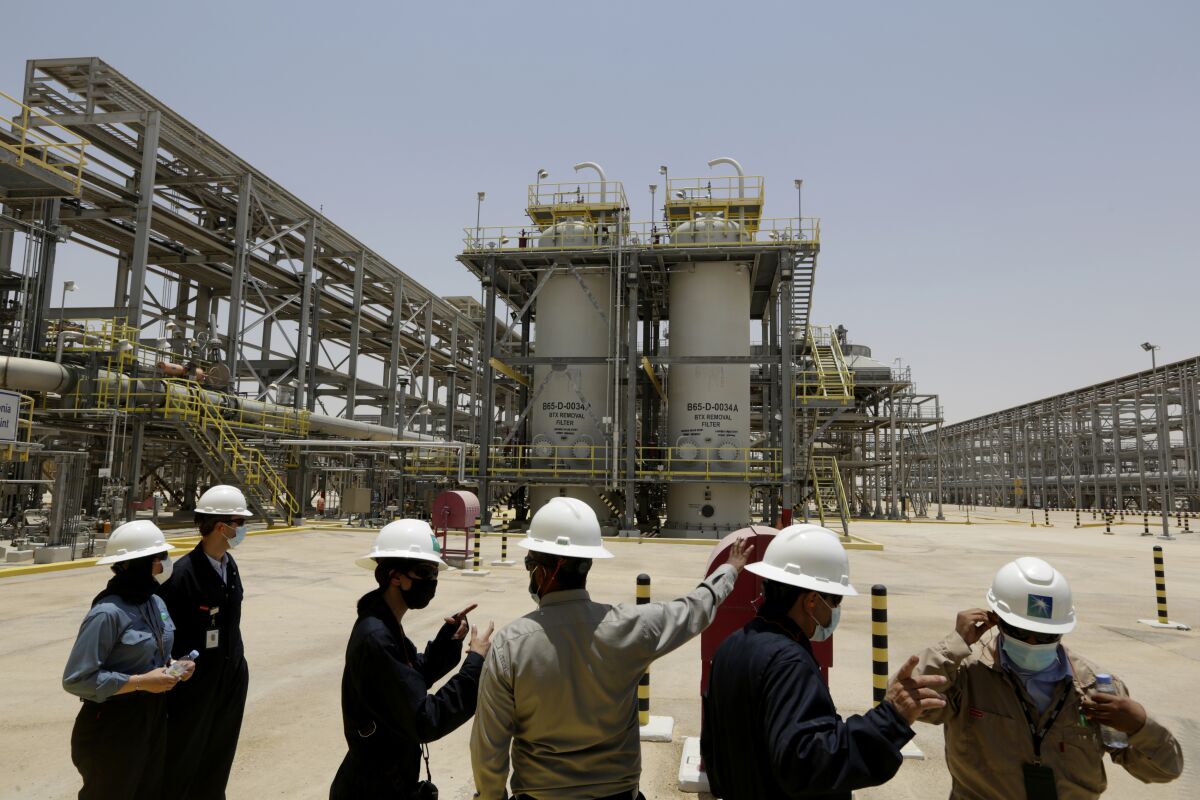 FILE - Saudi Aramco engineers and journalists look at the Hawiyah Natural Gas Liquids Recovery Plant, which is designed to process 4.0 billion standard cubic feet per day of sweet gas, a natural gas that does not contain significant amounts of hydrogen sulfide, in Hawiyah, in the Eastern Province of Saudi Arabia, June 28, 2021. Leaders of the world's most consequential energy bodies gathered for a forum Wednesday, Feb. 16, 2022, to discuss the uncertain future of oil as demand rebounds and prices climb, all while a growing roster of nations pledge to transition to cleaner forms of energy. (AP Photo/Amr Nabil, File)