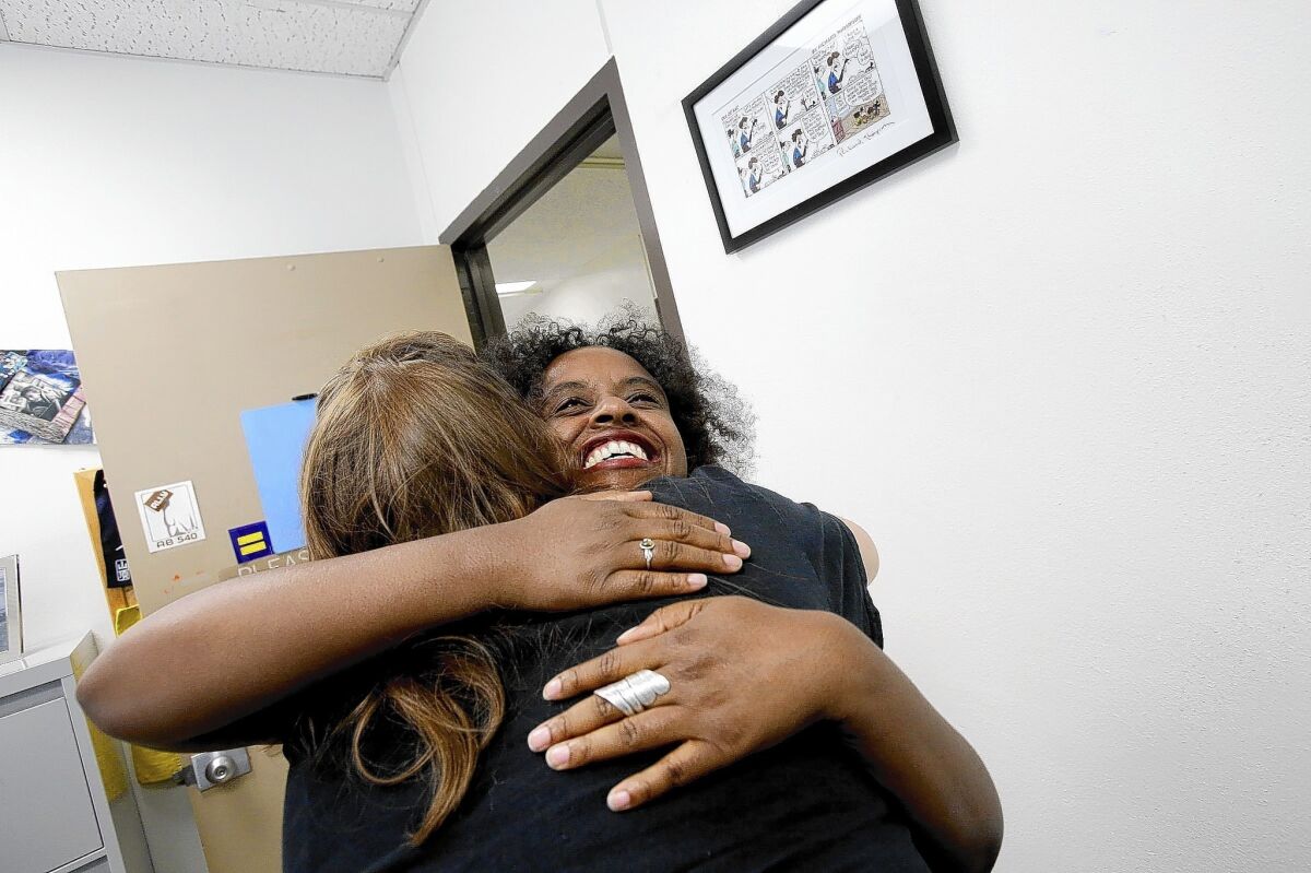 Rashida Crutchfield, right, gives a hug to Cal State Long Beach grad Brittany Urich. Crutchfield was a part-time lecturer in social work at the university but, in the university system's push to hire more full-time faculty, has been hired as an assistant professor starting in August.