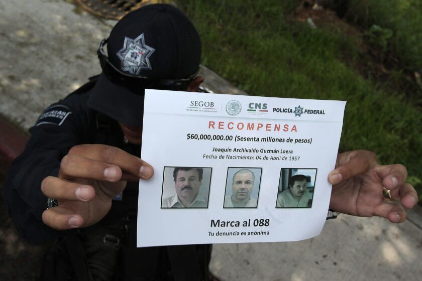 A police officer shows a reward notice on July 16 as members of Mexico's Federal Police continue investigating the escape of drug trafficker Joaquin "El Chapo" Guzman.