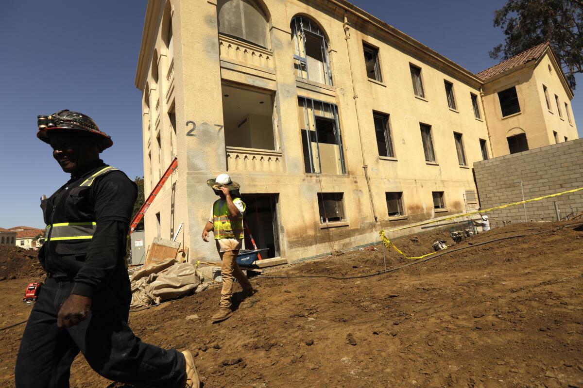 Construction workers walk past a building that is being refurbished 