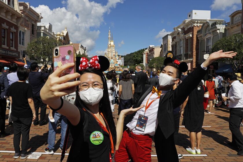 Visitors wearing face masks to prevent the spread of the new coronavirus, take a selfie at the Hong Kong Disneyland on Thursday, June 18, 2020. Hong Kong Disneyland on Thursday opened its doors to visitors for the first time in nearly five months, at a reduced capacity and with social distancing measures in place. The theme park closed temporarily at the end of January due to the coronavirus outbreak, and is the second Disney-themed park to re-open worldwide, after Shanghai Disneyland. (AP Photo/Kin Cheung)