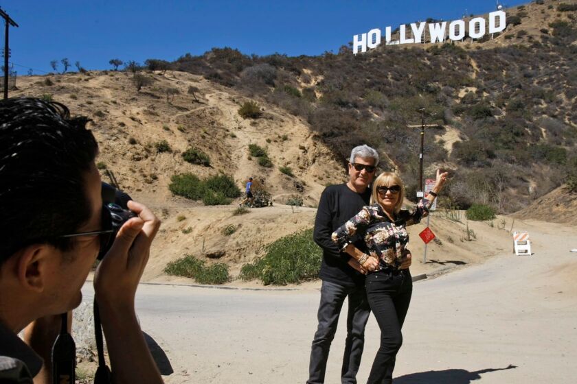 LOS ANGELES, CALIFORNIA - SEPTEMBER 26, 2013: Silvestre Llobet and his wife Elena Domenech are photographed by their son, Alejandro Llobet (left) under the Hollywood sign on September 26, 2013 in the Beachwood Canyon area of Los Angeles. Silvestre and Elena are visiting from Barcelona, Spain. Residents in the Beachwood Canyon area of Los Angeles are fighting with the Hollywood Homeowners Association over tourists looking at the Hollywood sign. (Gary Friedman/Los Angeles Times)