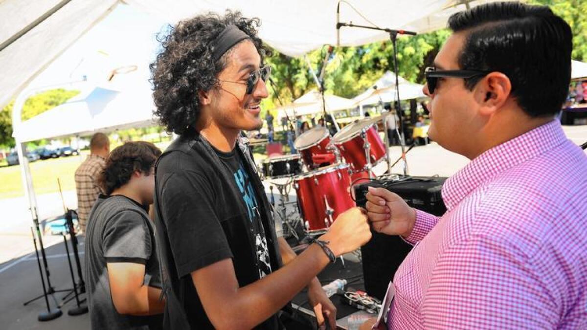 Jonathan Jiménez, a la izquierda, organizador del Maywood Music Festival, le da las gracias a un miembro del grupo Whiskey Dynamos después del concierto.