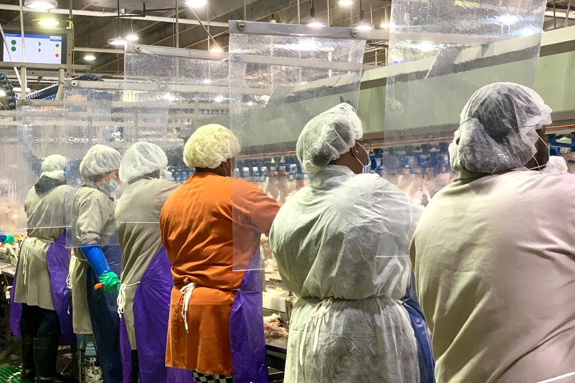 Workers wear protective masks and stand between plastic dividers at Tyson Foods' Camilla, Ga., poultry processing plant.