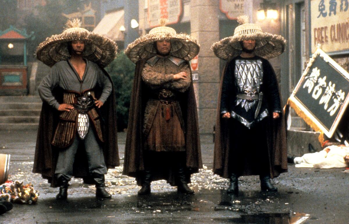 Three swordsmen stand in an alleyway.