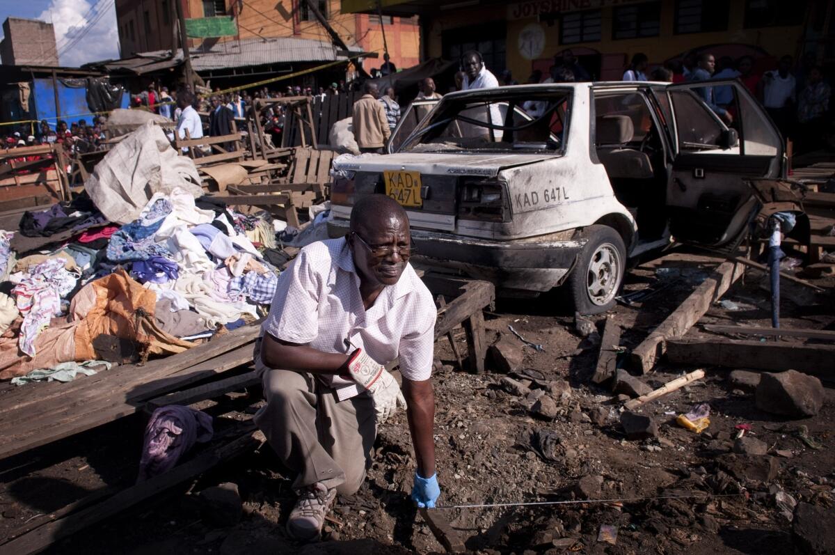 A member of the bomb squad measures the distance between two blast sites after two bombs went off Friday in the Gikomba market in Nairobi, Kenya.