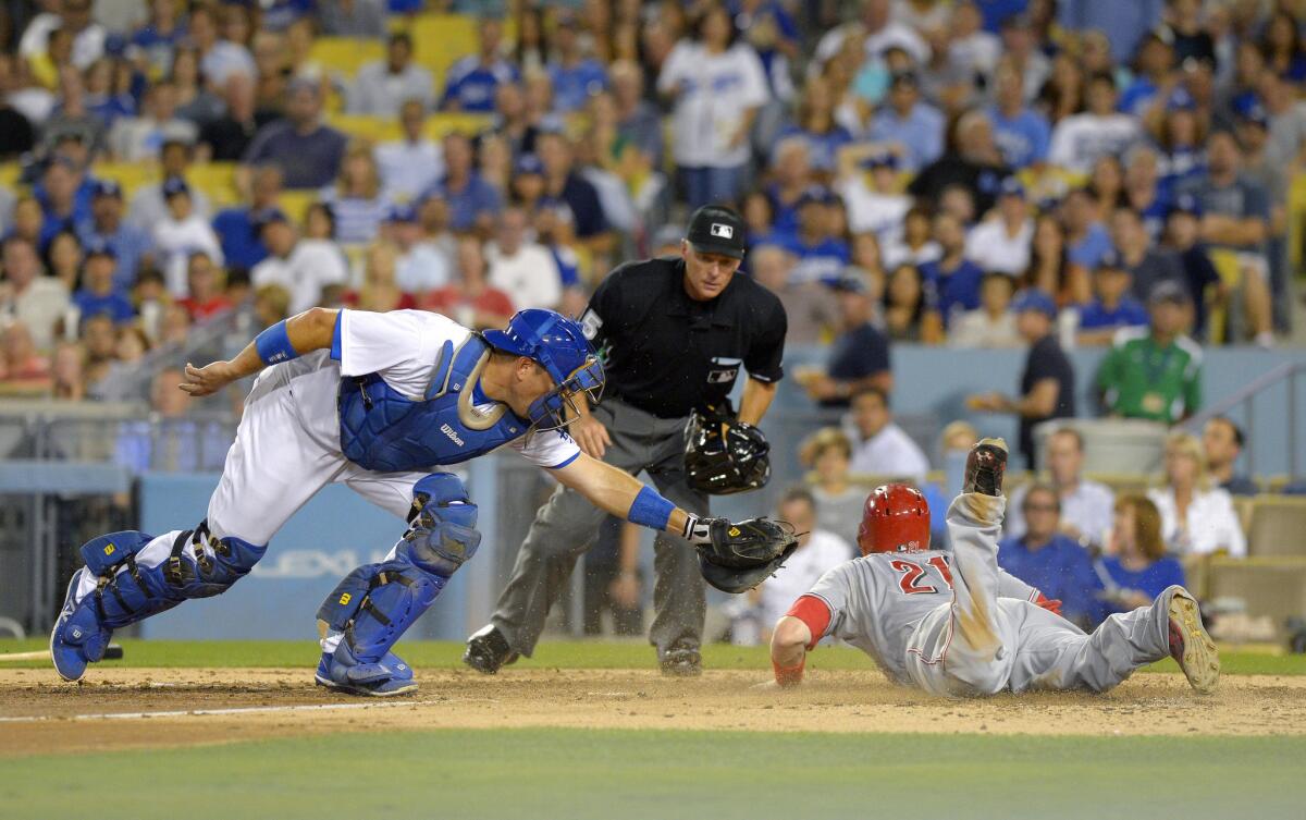 Reds third baseman Todd Frazier dives past the tag of Dodgers catcher A.J. Ellis on a sacrifice fly by Jay Bruce as umpire Ed Hickox watches.
