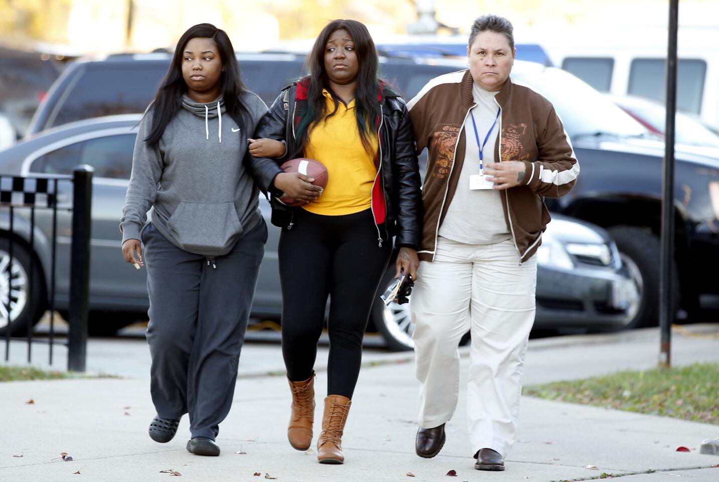 Holding a football and her son's photo, Karla Lee, center, arrives at Chicago Police District Area 5 headquarters on Nov. 3, 2015, to ask the public to help find the person who shot and killed her 9-year-old son Tyshawn Lee the day before.