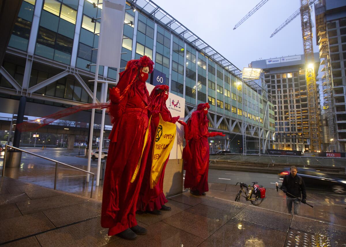 Demonstrators in red dresses hold a banner outside a court building