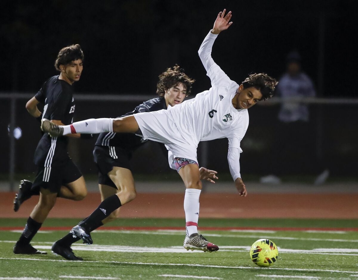 Costa Mesa's Carlos Alcala is tripped up as he defends against Estancia on Wednesday.