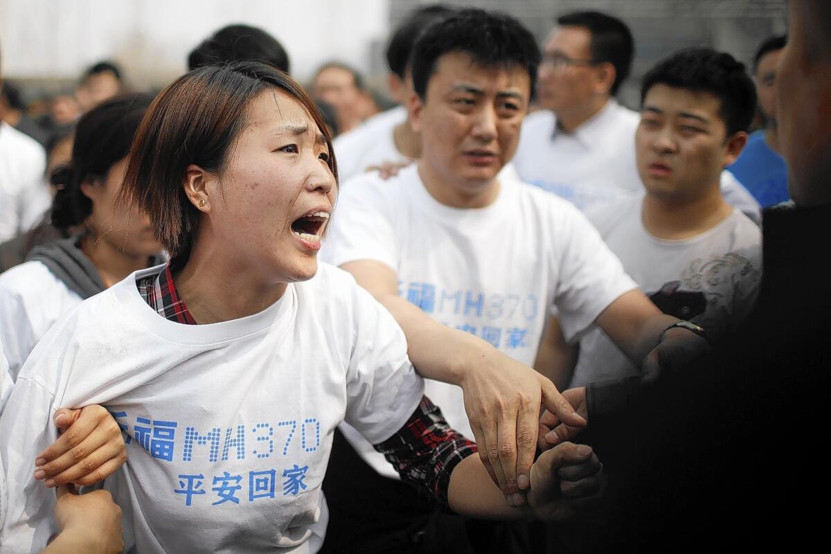A relative of passengers on missing Malaysia Airlines Flight 370 yells at security personnel during a protest outside the Malaysian Embassy in Beijing.