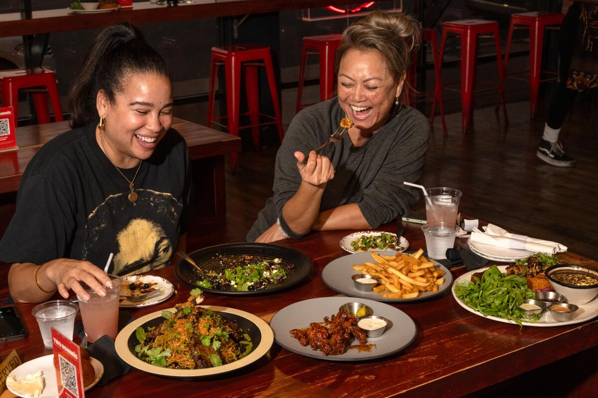 Two customers laughing with dinner plates spread across the table
