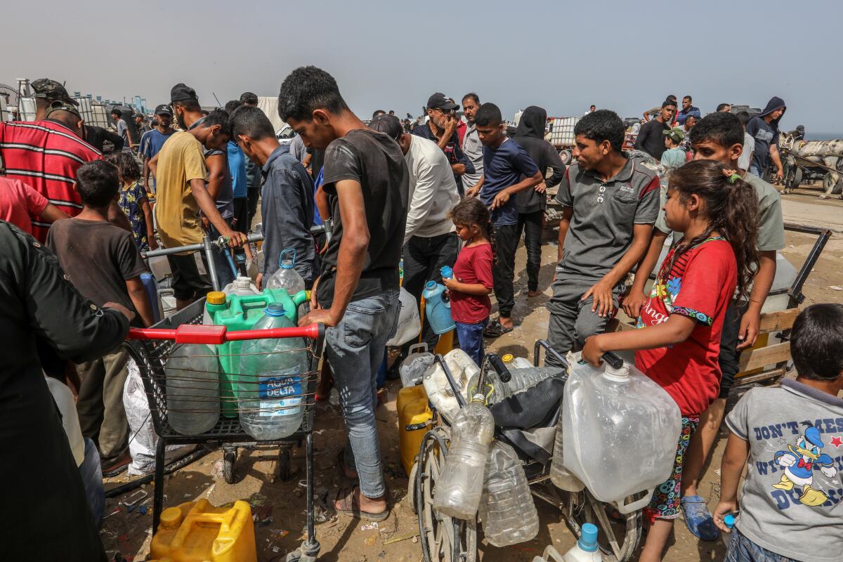 Palestinians line up to receive drinking water distributed by aid organizations in Gaza.