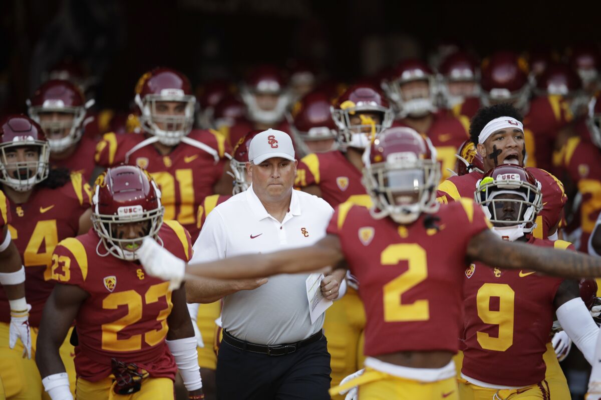 USC coach Clay Helton, center, runs onto the field with his team before a game against Utah on Sept. 20, 2019 at the Coliseum.