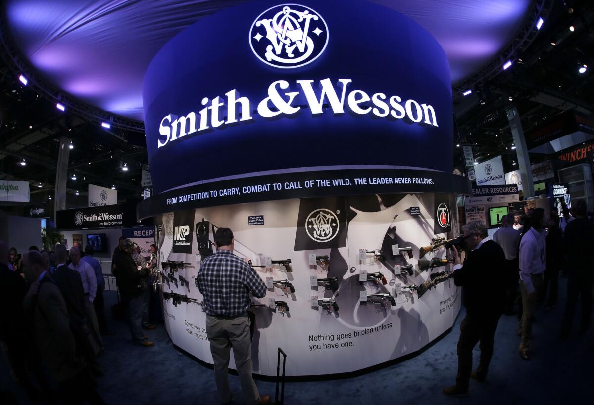 Trade show attendees examine handguns and rifles in the Smith & Wesson display at the Shooting, Hunting and Outdoor Tradeshow in Las Vegas.