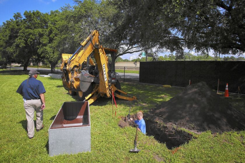 Richard Ossorio with Quality Vaults, Inc., right, and Owl Goingback, left, with Greenwood Cemetery dig the first of three graves for Pulse nightclub victims at Greenwood Cemetery in Orlando on June 16, 2016. The city of Orlando offered plots to all 49 victims' families, free of charge.