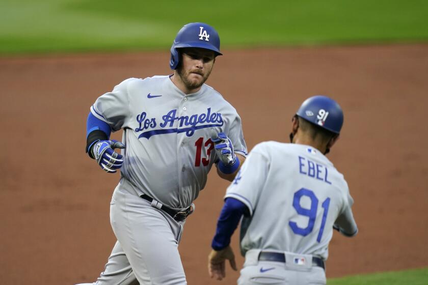 Los Angeles Dodgers' Max Muncy (13) is greeted by third base coach Dino Ebel as Muncy runs the bases on his solo home run against the Seattle Mariners during the second inning of a baseball game Wednesday, Aug. 19, 2020, in Seattle. (AP Photo/Elaine Thompson)