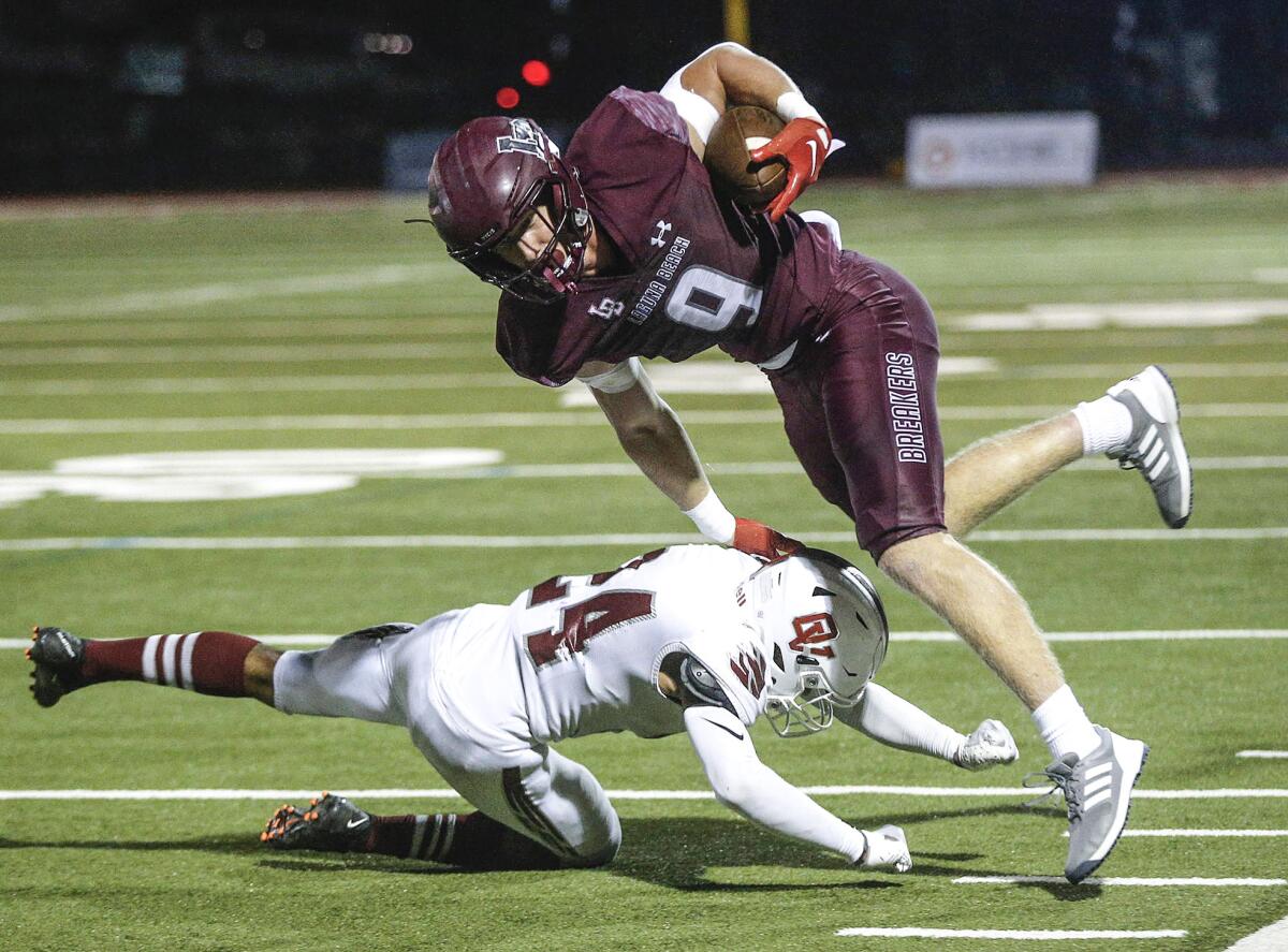 Ryner Swanson (9) of Laguna Beach is tripped up close to the end zone by Ocean View's Devyn Jenkins.