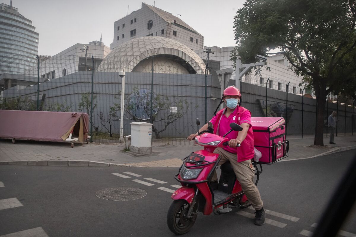 A delivery driver waits to cross an intersection near the Israeli Embassy in Beijing, Wednesday, May 19, 2021. Israel's Embassy in China is protesting what it describes as "blatant anti-Semitism" on a program run by the overseas channel of state broadcaster CCTV discussing the ongoing violence in Gaza and elsewhere. (AP Photo/Mark Schiefelbein)