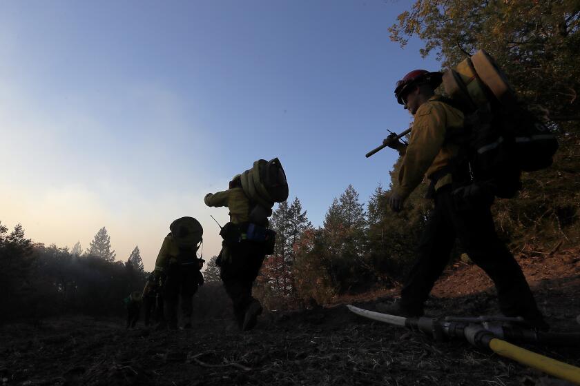 HEALDSBURG, CALIF. - OCT. 28, 2019. Firefighters lay hose lines along Ida Clayton Road near the head of the Kincade fire in Sonoma County on Tuesday, Oct. 29, 2019. (Luis Sinco/Los Angeles Times)