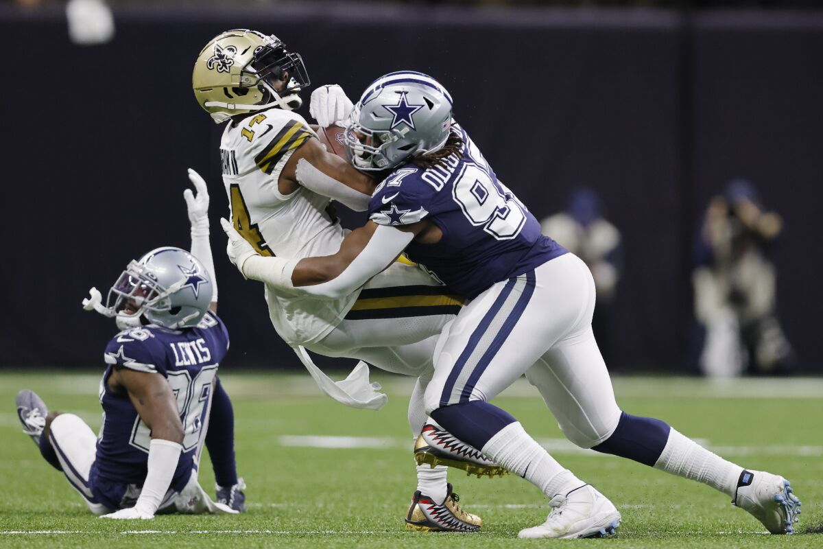 New Orleans Saints wide receiver Kawaan Baker is hit by Dallas Cowboys defensive tackle Osa Odighizuwa.