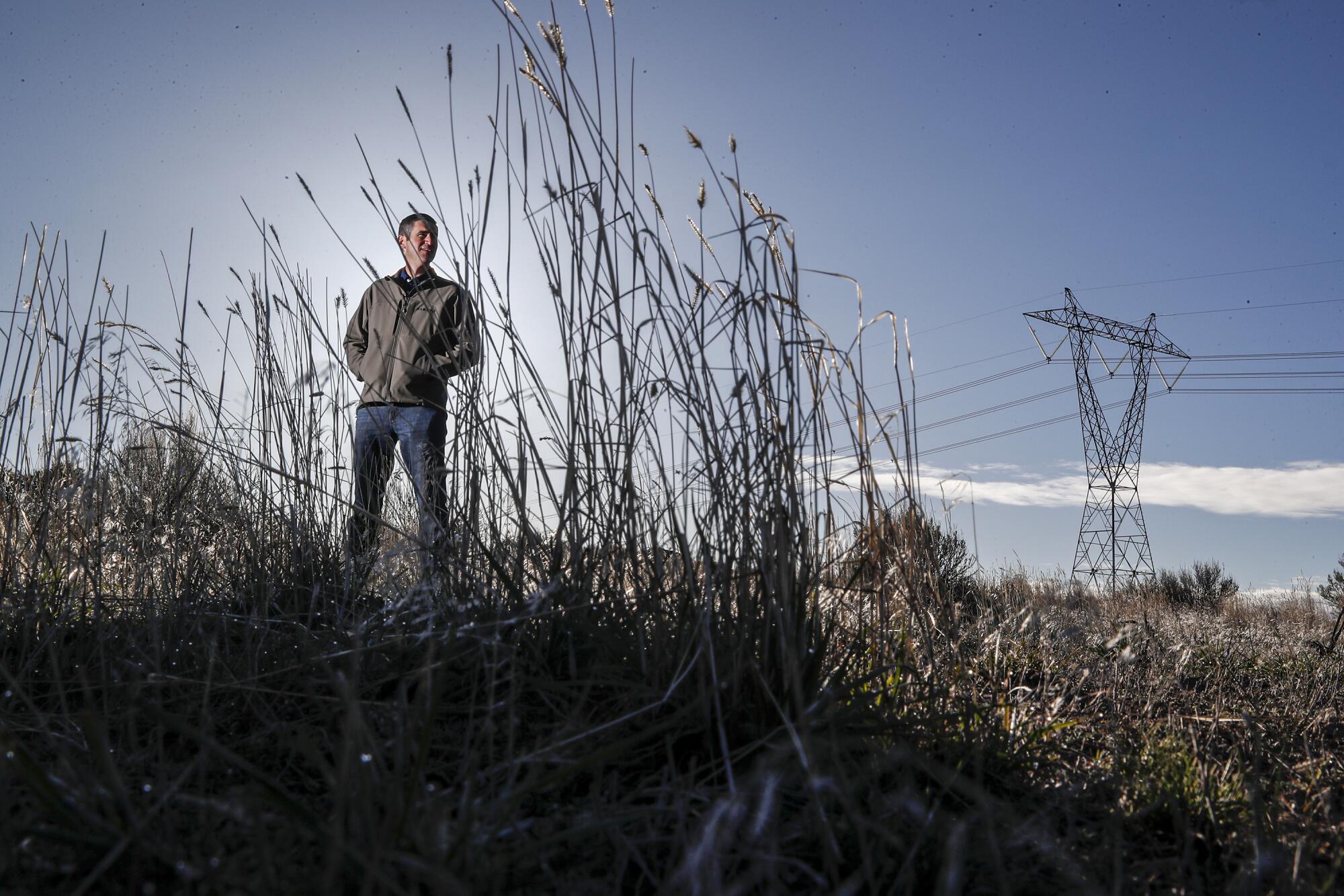 A man stands near electric lines.