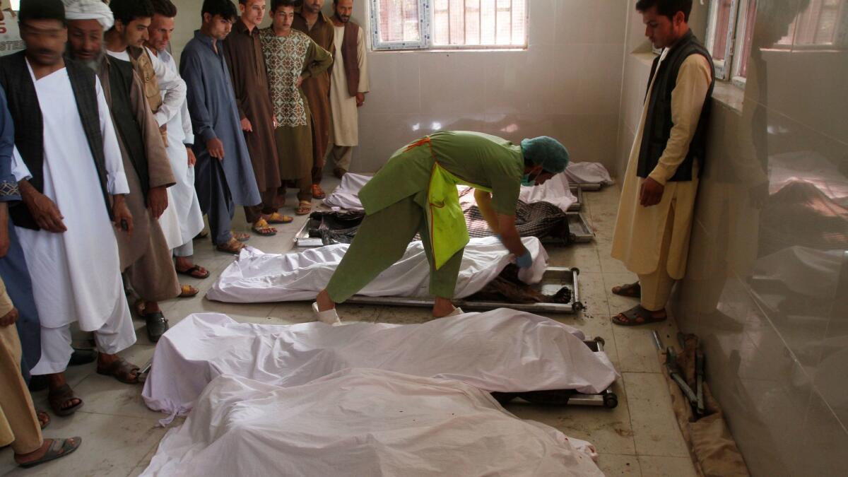 Men stand near the bodies of their relatives June 6 in a hospital near the site of an explosion in western Herat city, Afghanistan.
