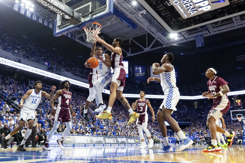 Kentucky guard Sahvir Wheeler (2) passes the ball off while being guarded by Mississippi State guard Iverson Molinar, behind Wheeler, and forward Garrison Brooks, right, during the first half of an NCAA college basketball game in Lexington, Ky., Tuesday, Jan. 25, 2022. (AP Photo/Michael Clubb)