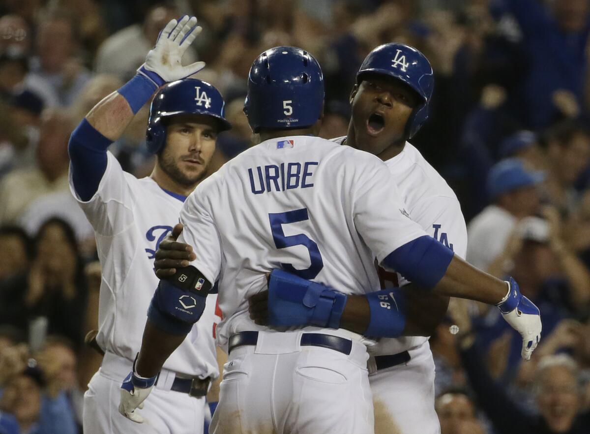 Juan Uribe is greeted by Yasiel Puig and Skip Schumaker after hitting a two-run homer against the Braves in Game 4 of the NLDS on Oct 7, 2013.