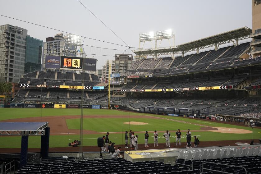 San Francisco Giants stand near the dugout as the team's baseball game against the San Diego Padres is postponed Friday, Sept. 11, 2020, in San Diego, minutes before the scheduled first pitch. No reason was immediately given. (AP Photo/Gregory Bull)