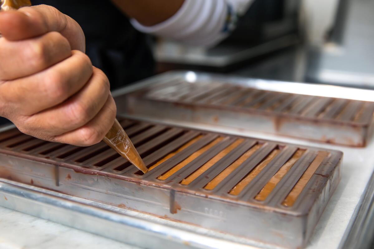 Pastry chef Mac Daniel Dimla works in the kitchen of Providence's, piping chocolate into molds. 