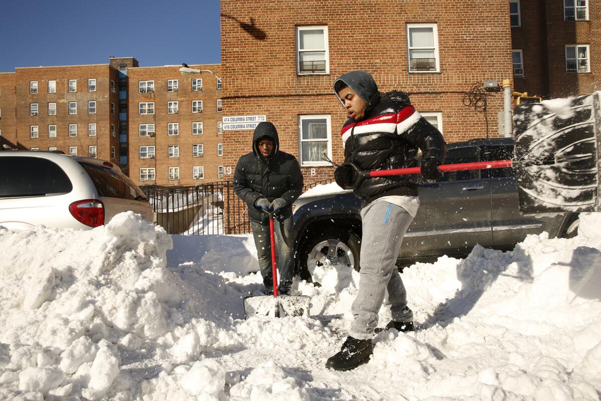 John Ruiz, 18, right, and Tyrone Graham, 16, earn money digging cars out of the snow in the Red Hook neighborhood of Brooklyn, N.Y.