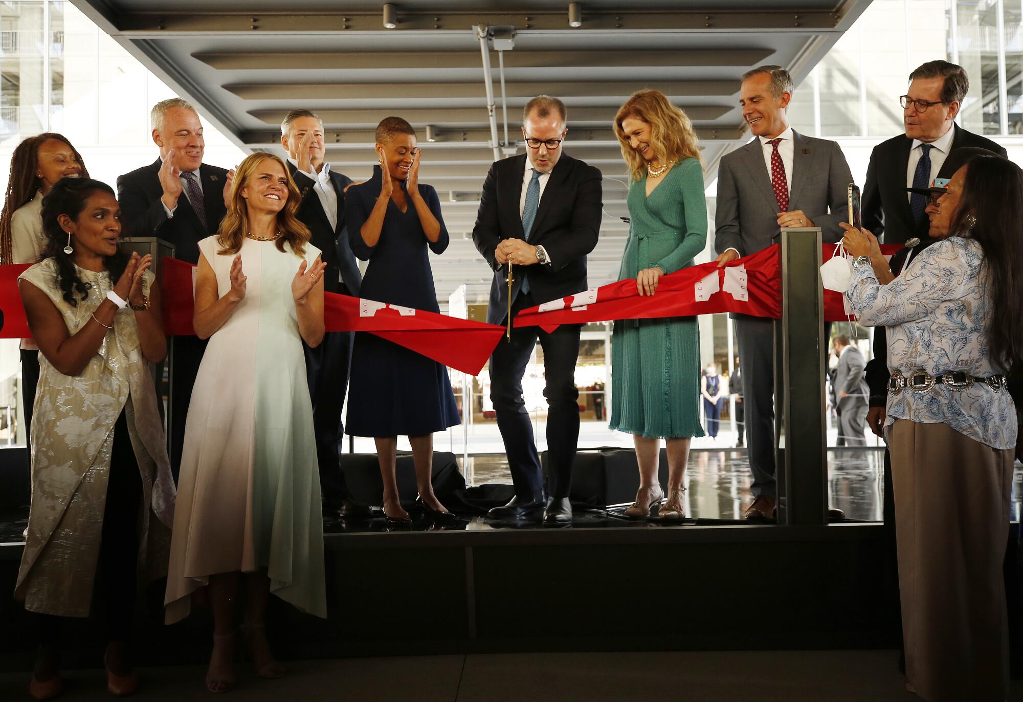 A group of people cut the red ribbon at the Academy Museum on opening day.