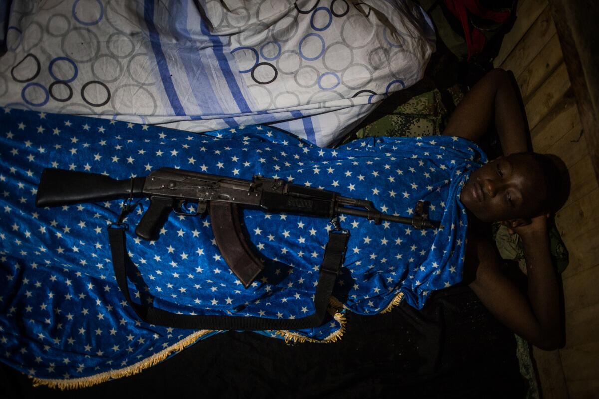 A young guerrilla fighter rests at night. The rebels must have their weapons at every moment.